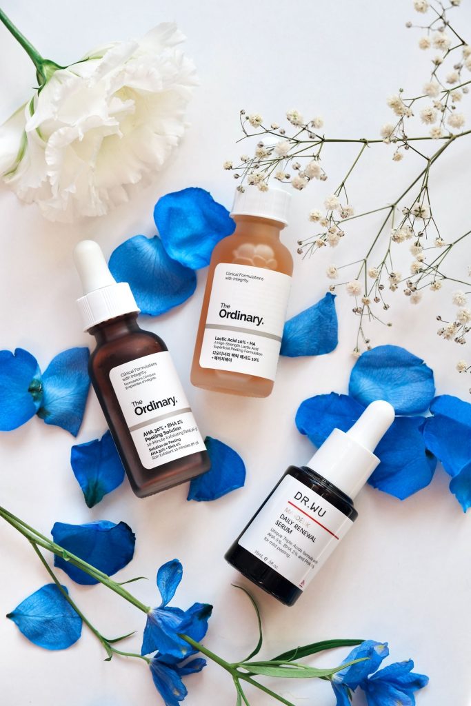 Skincare flat lay with blue petals and serums
